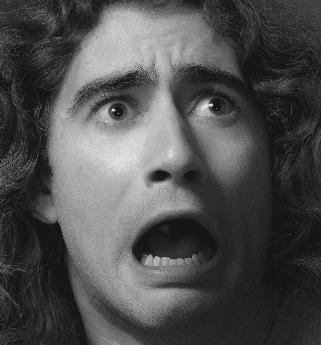 A black and white image of a man, mouth wide open looking shocked