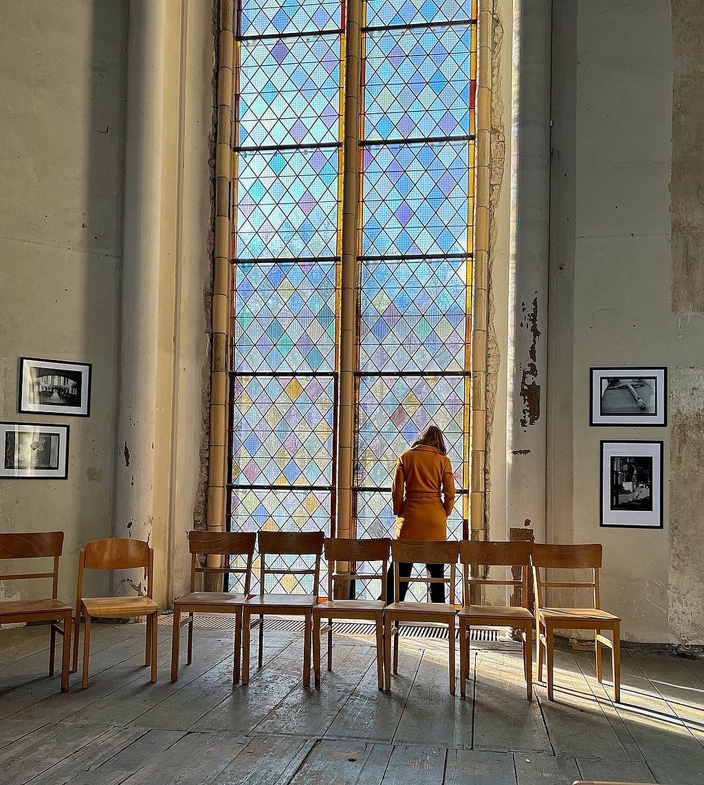 Woman meditating in-front of a church window.
