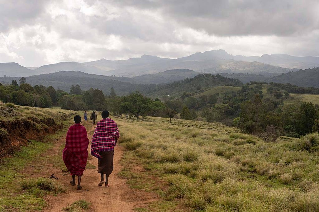 Walking on the path to a sacred cave, with the peaks of Mount Elgon in the distance.