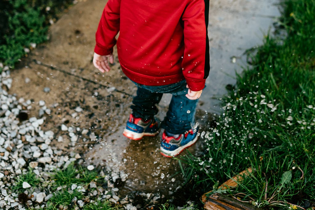 A boy splashing in rain water