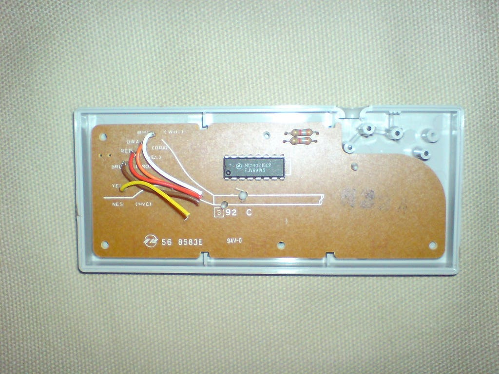 An original Nintendo controller with the back taken off. Showing circuit board and snipped cable bundle.