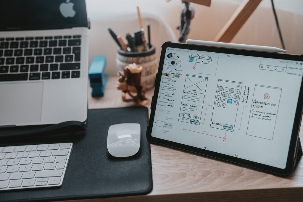 A tablet with wireframe sketches on a wooden desk