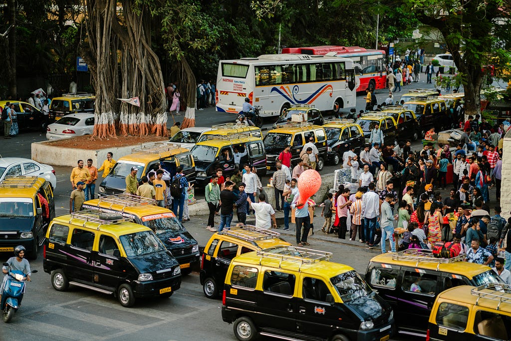 Bustling Mumbai city with traffic — cabs, buses and people milling around