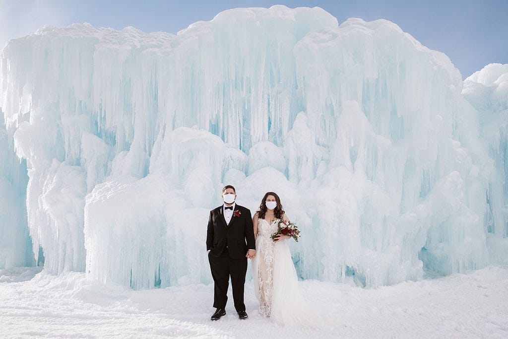 A bride and groom in front of a glacier.