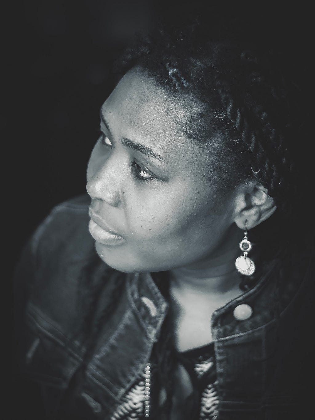 A side profile of an African woman wearing earrings and staring off into the distance in a dignified way.