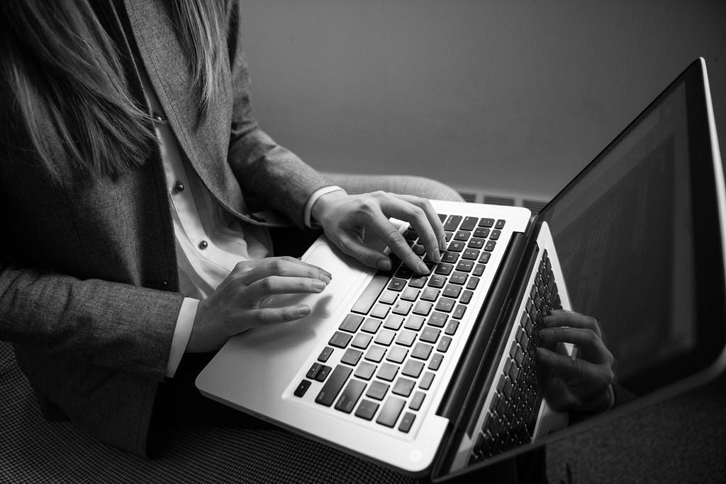 A black and white photo of a lady working on her laptop