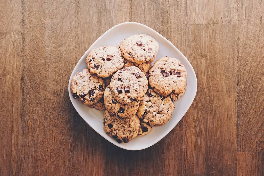 A big white plate covered in piles of small chocolate chip cookies