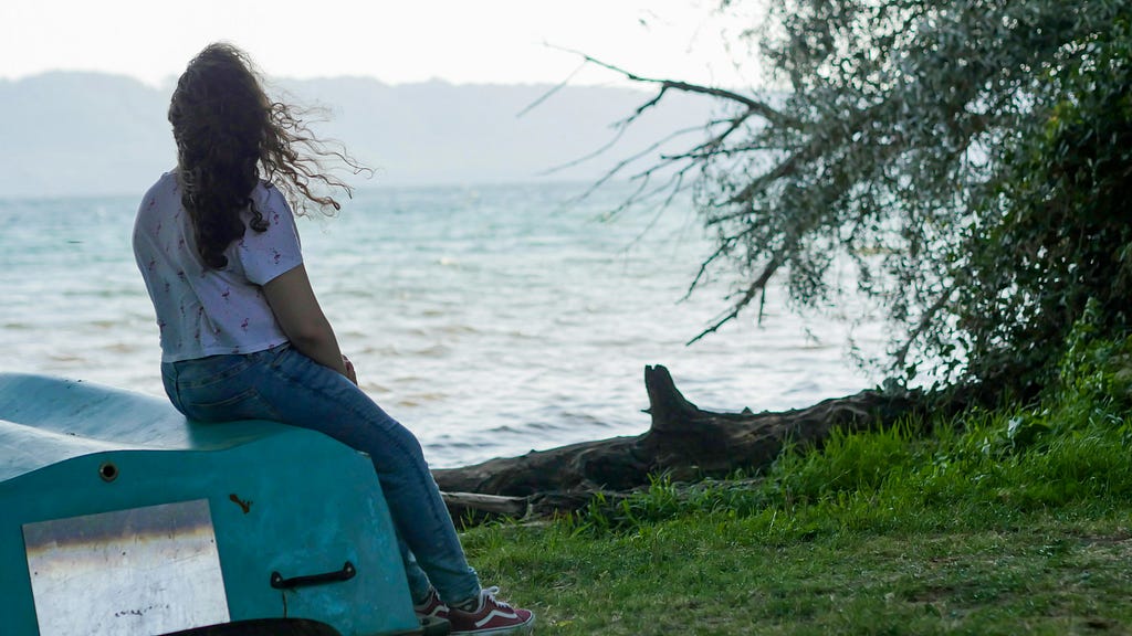 A girl enjoying and watching the beach view alone at the water’s edge