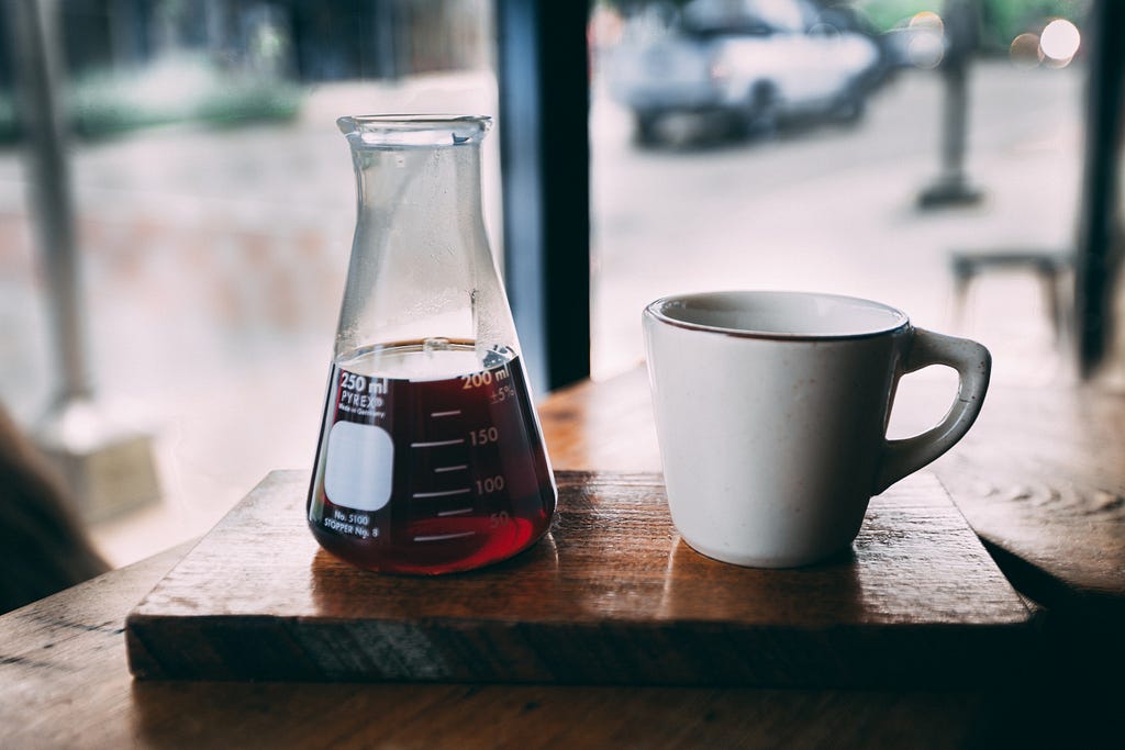 Beaker with Liquid next to Coffee Mug