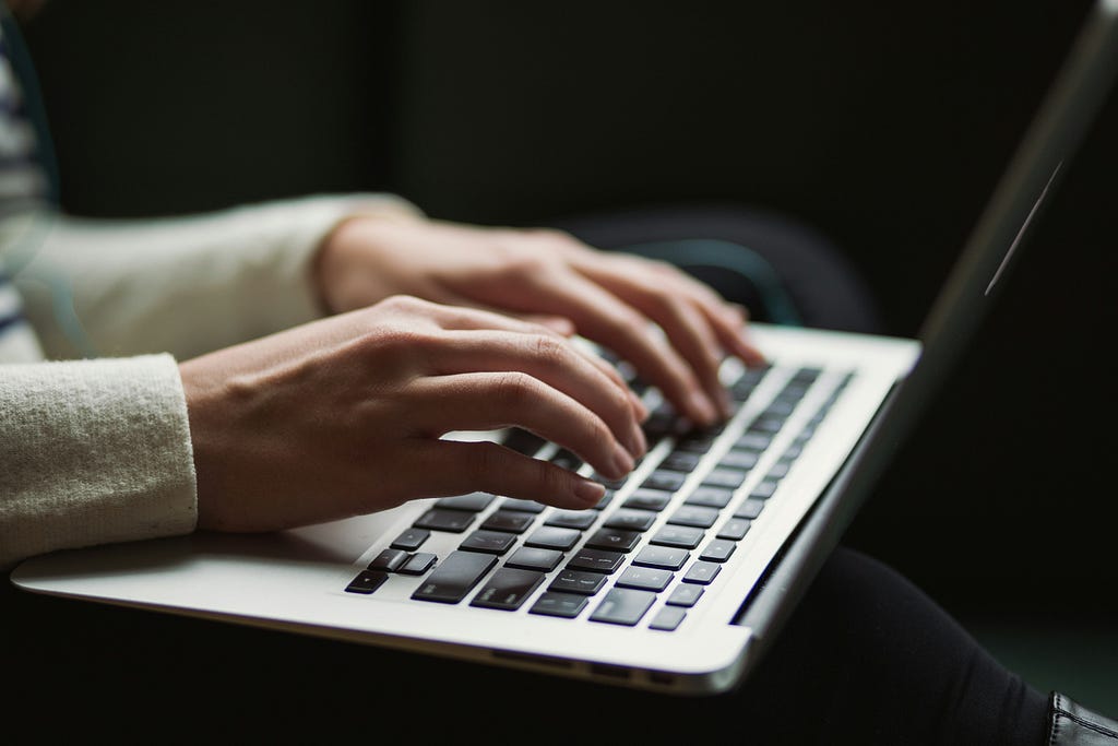 Woman writing on a laptop keyboard, soft focus.