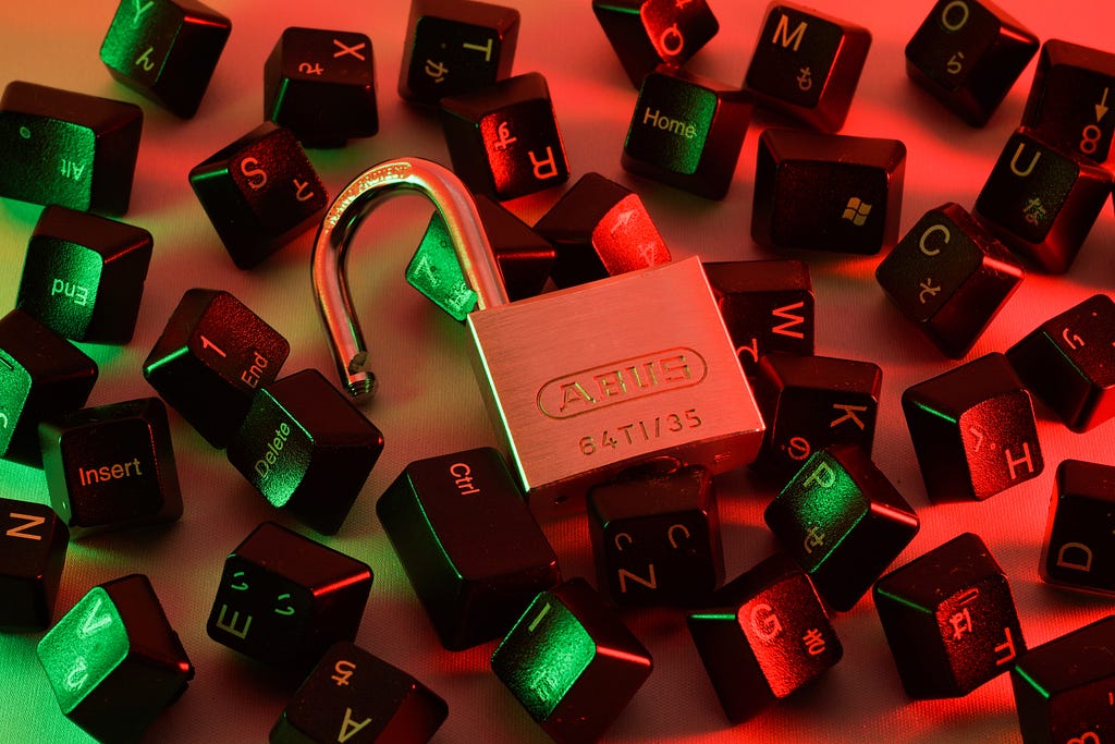 An open padlock resting on a jumble of keyboard keys