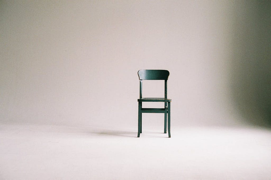 A black chair in an empty white room