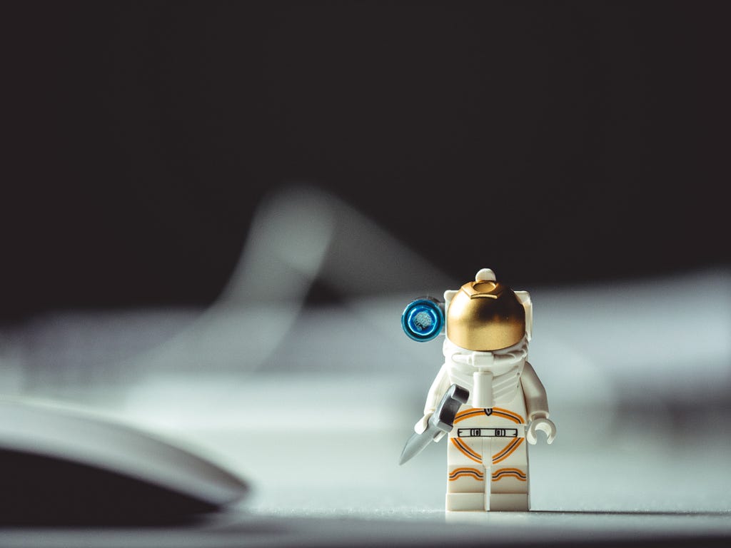 A tiny astronaut toy standing on the desk