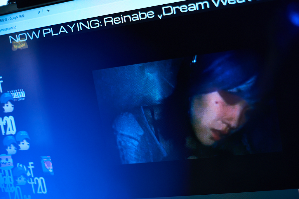 A picture of a browser tab open where a livestream shows a blue-haired girl with headphones intensely DJ.