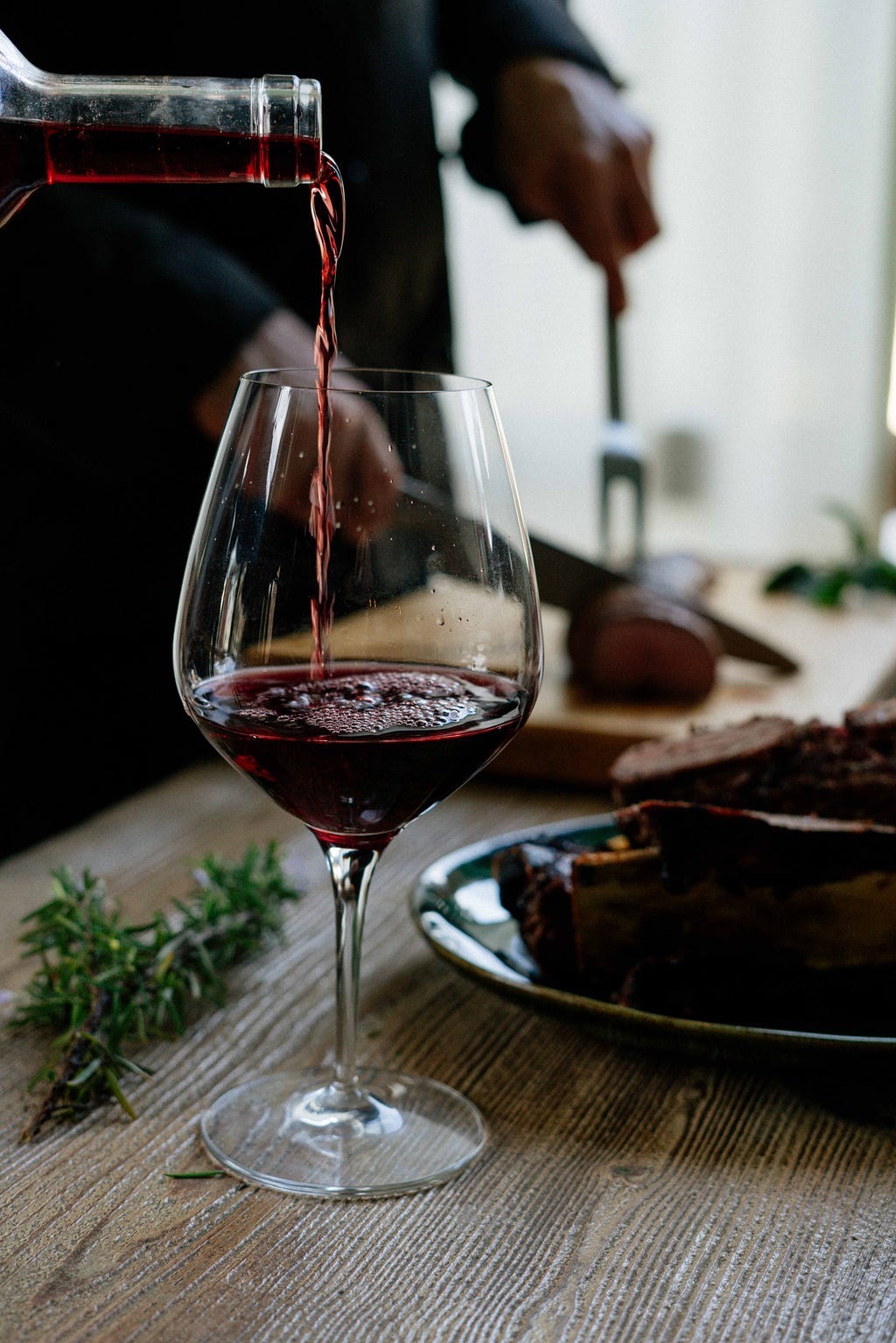 A close-up of a red wine being poured into a wine glass.