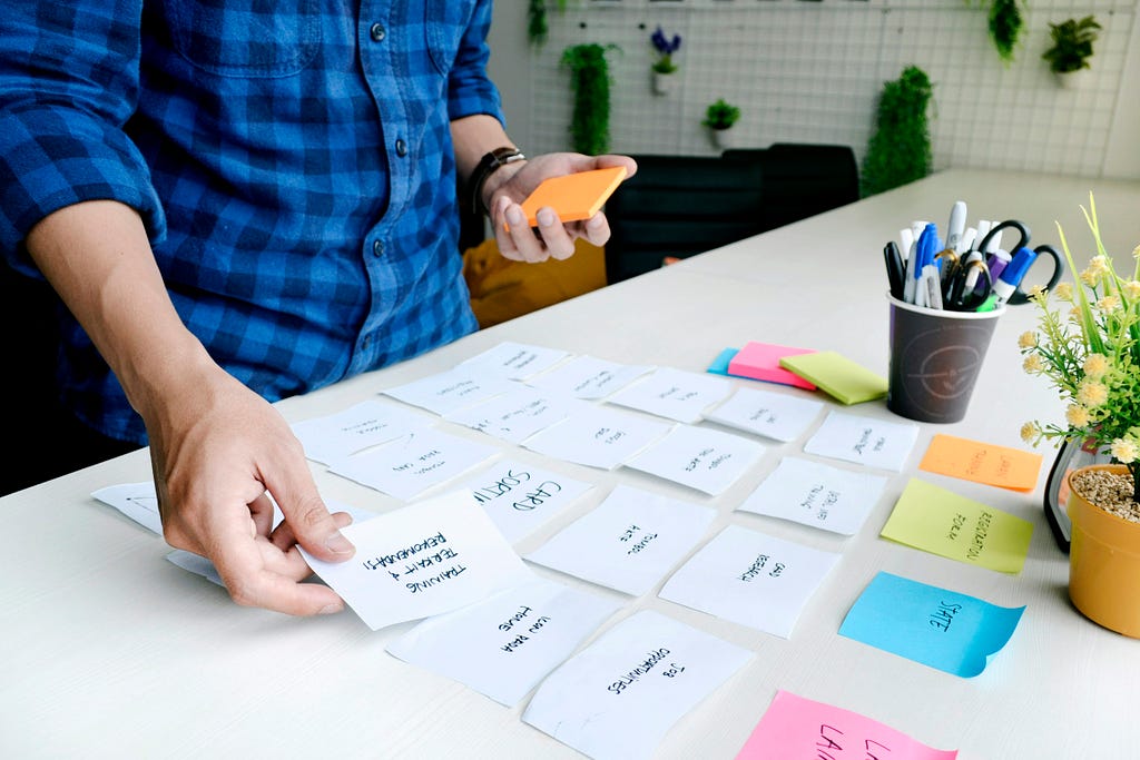 Designer organising notes on a table to represent card sorting.