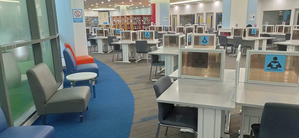 Chairs and tables with rows of books behind in Sunway University’s library