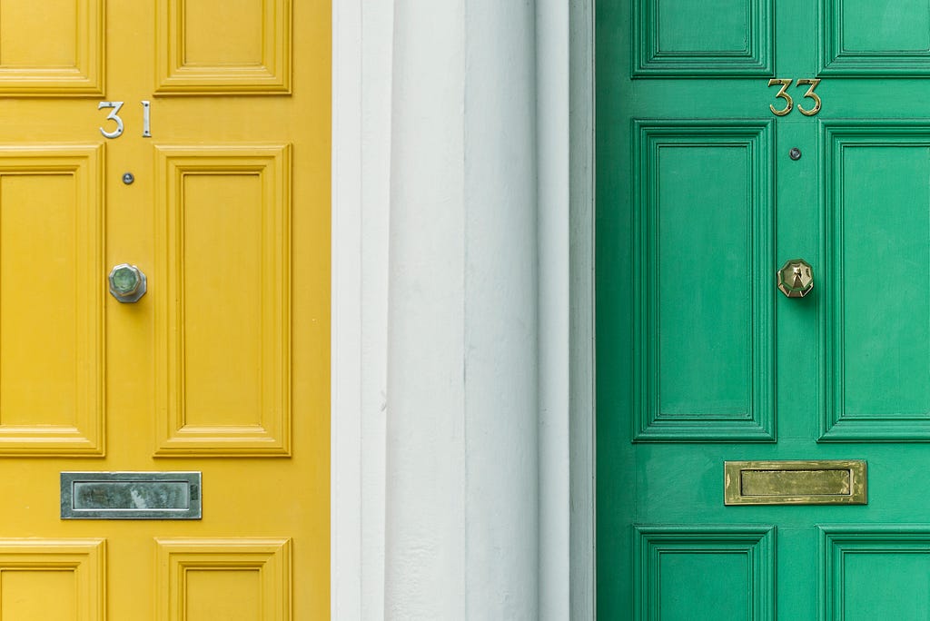 A yellow and green door of apartments next to each other