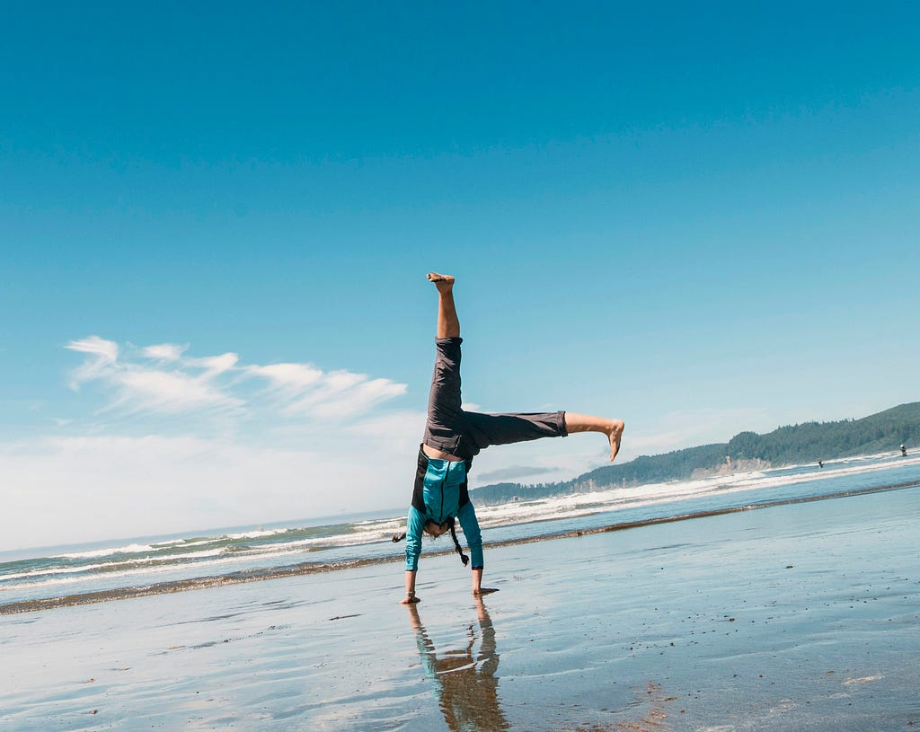 brown-haired girl turning cartwheels at low tide