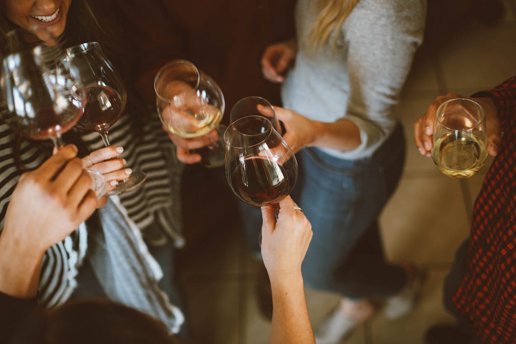 People raising a glass of wine together. Happily socializing.