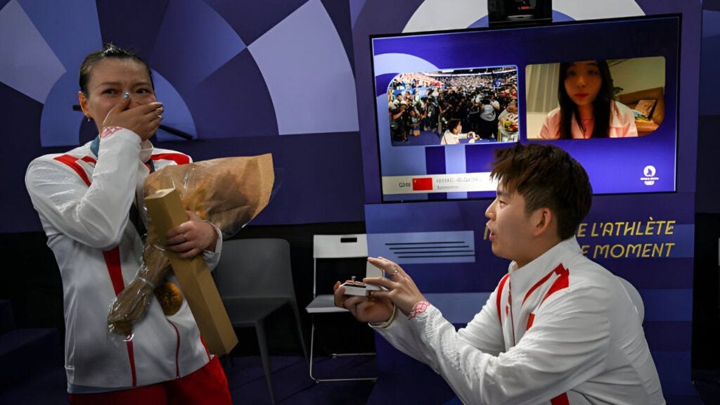 China's Liu Yuchen proposes to his partner and gold medalist Huang Ya Qiong after leaving the podium at the mixed doubles badminton medal ceremony at the Paris 2024 Olympic Games at Porte de la Chapelle Arena on August 2, 2024. ARUN SANKAR/AFP / 