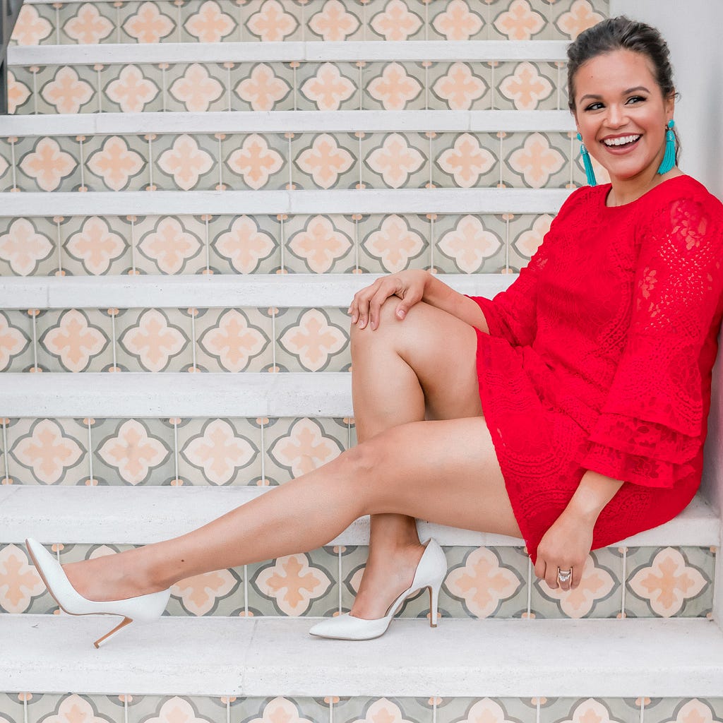 smiling woman in red dress sitting on stairs