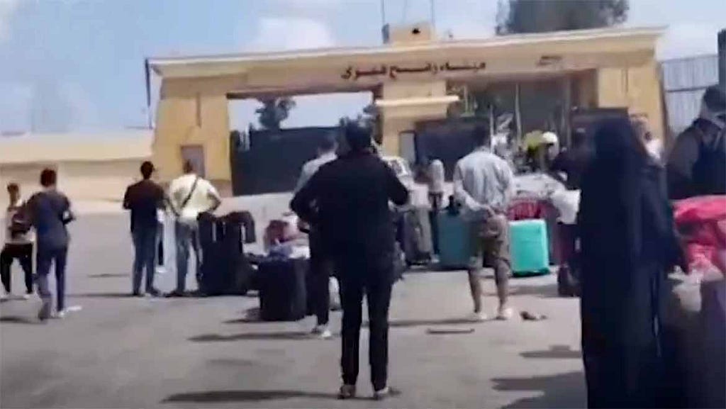 People waiting at the Rafah border crossing to go into Egypt. They have bags.