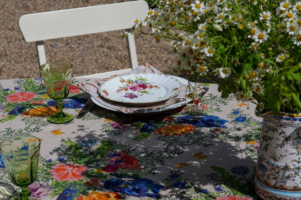 Floral organic linen tablecloth set with vintage crockery on an outdoor table.