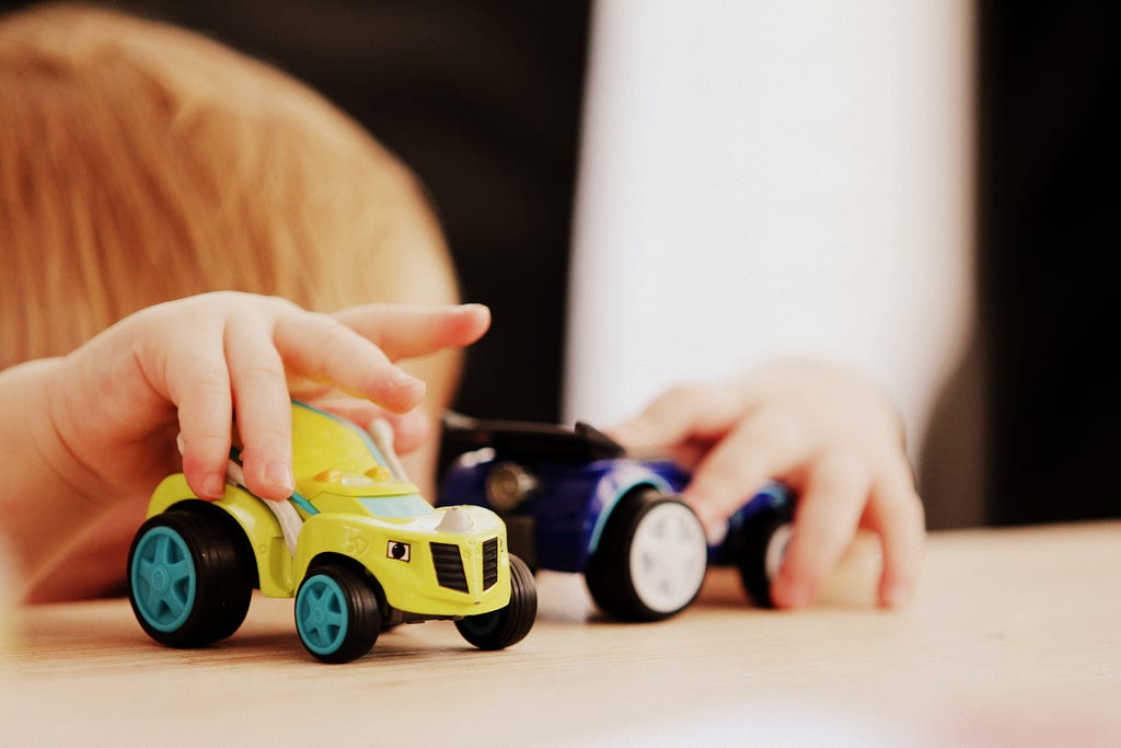 Toddler’s hands holding two toy cars