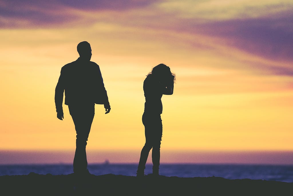 Silhouetted couple, woman with head down as if crying