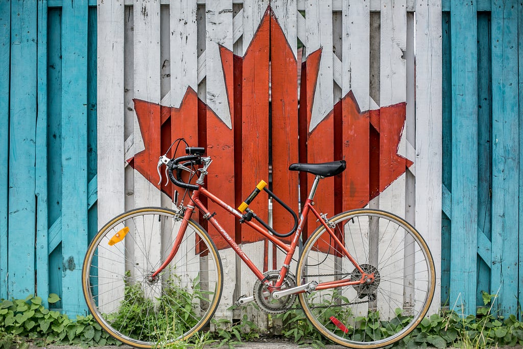 A bike leaning up against a wall with a painted maple leaf