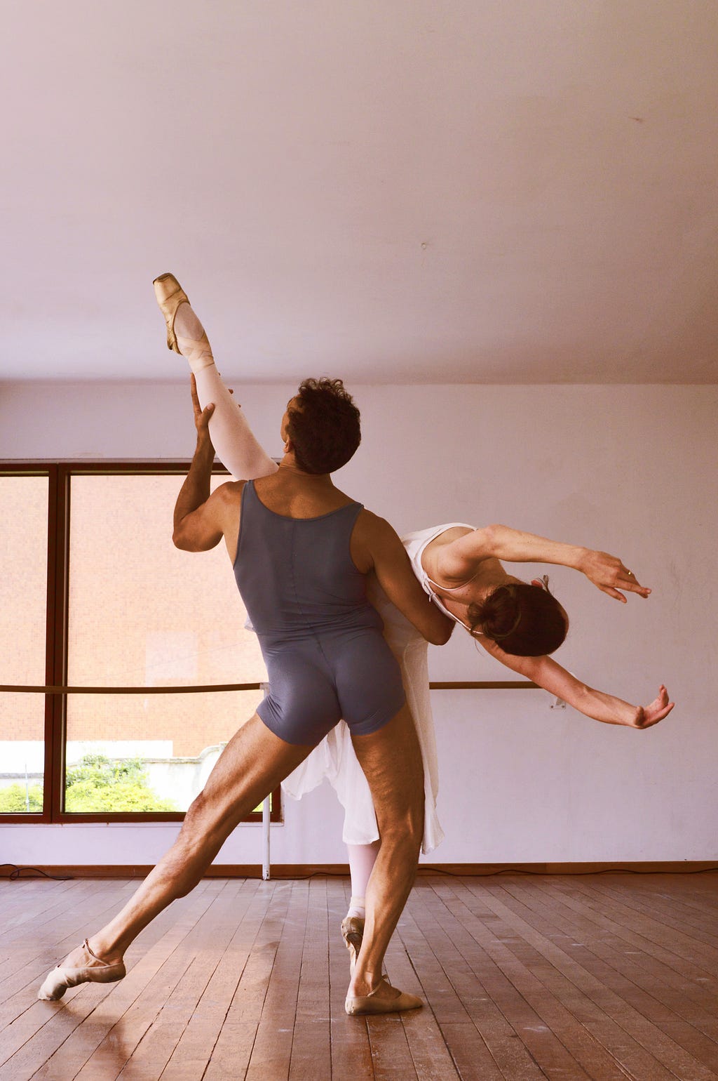 A male ballet dancer holding up a female ballet dancer as she performs.