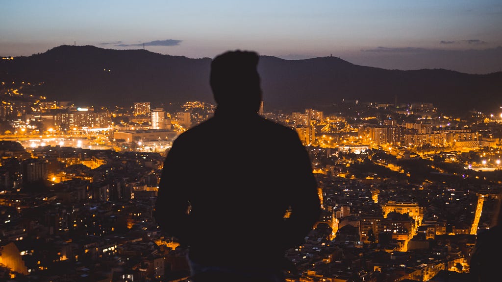 Silhouette of a man in front of the panorama of a city illuminated at night