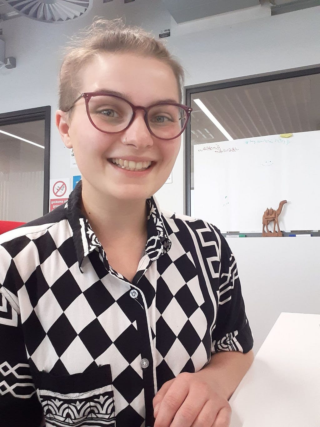a person with short hair, glasses and a black and white checked shirt