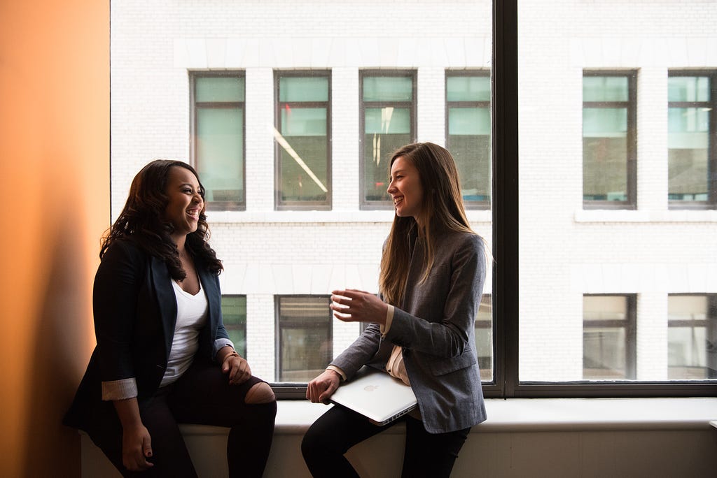 A Black woman and woman of color talking together in an office