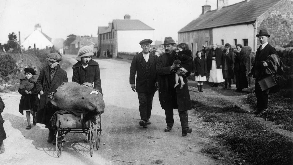 A black and white photograph of 1920s Irish people evacuating a village