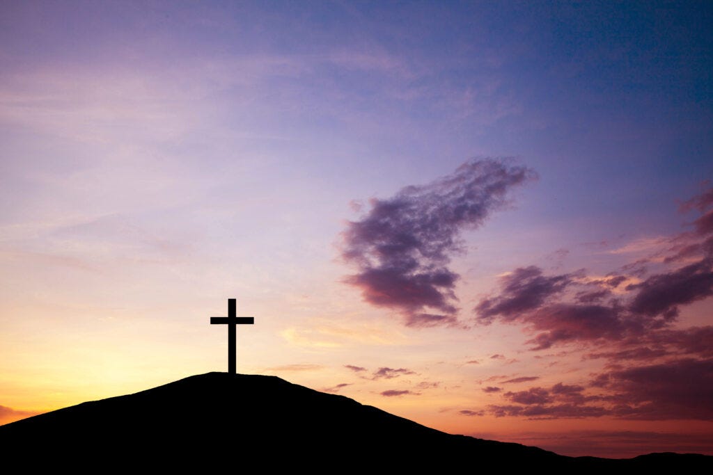 Cross on a hill at sunset — History of Easter