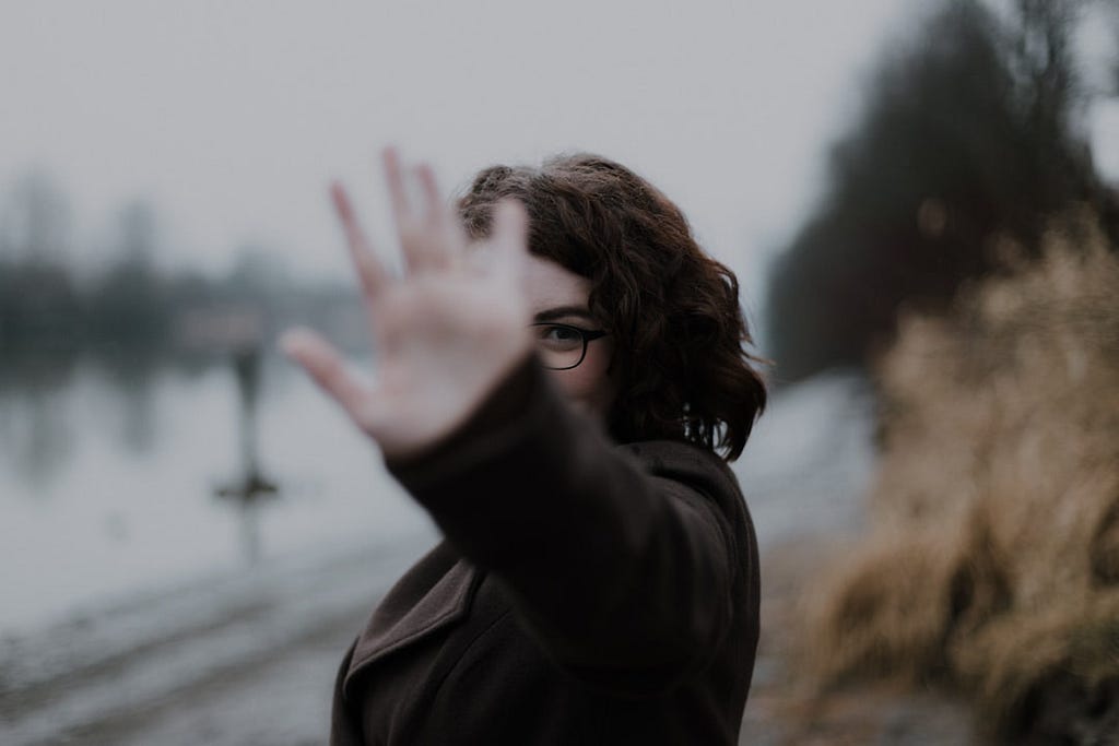 Woman with her hand towards the camera in a defying gesture