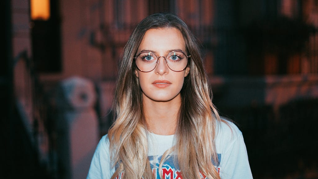 Portrait of a woman with glasses looking directly at the viewer.