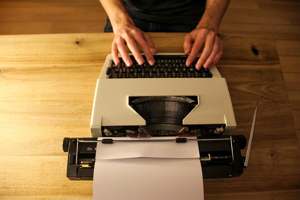 Person writing at a typing machine.