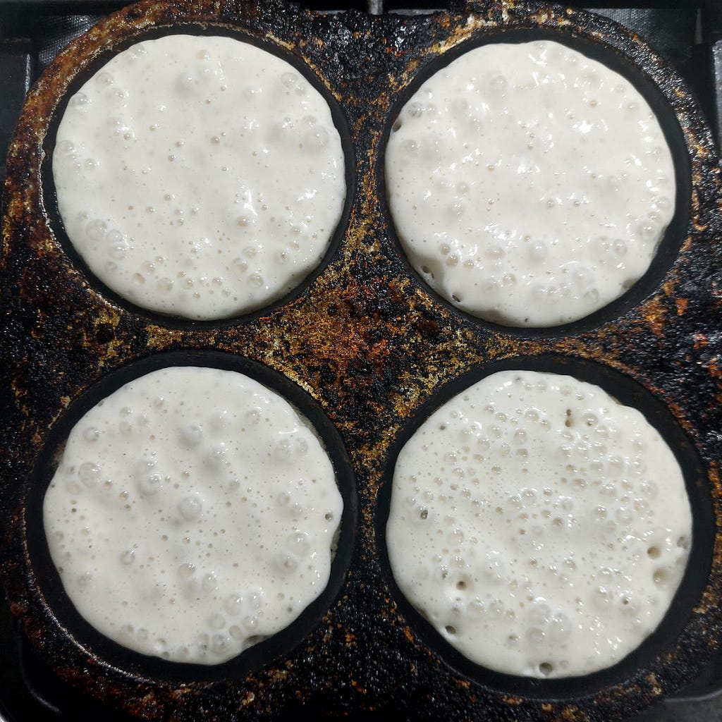 Masa in a pan showing bubbles and ready to be flipped.