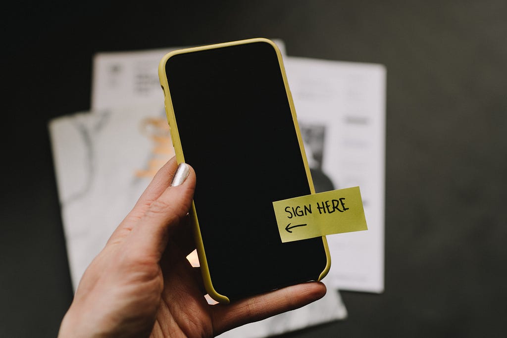 A smartphone with a post-it saying “Sign here”