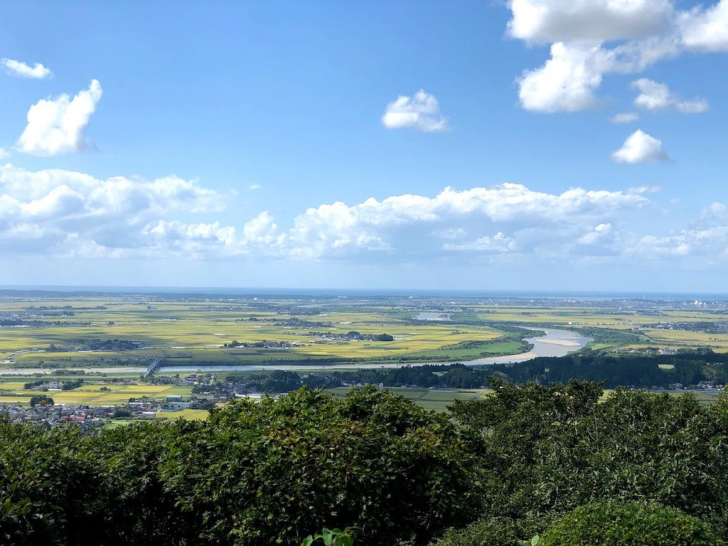 An expansive view over the Mogami River and the rice fields of the Shonai Plains in Sakata, near Mt. Kyogakura, one of the 100 Famous Mountains of Yamagata in the Tohoku region of North Japan.