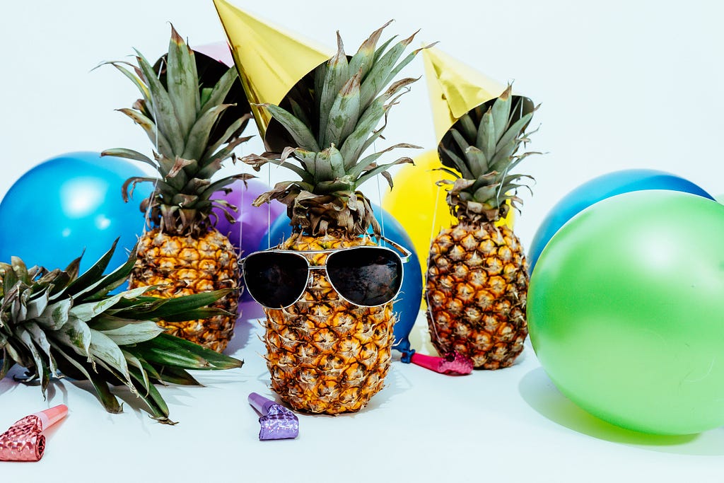 Pineapples with sunglasses on and balloons