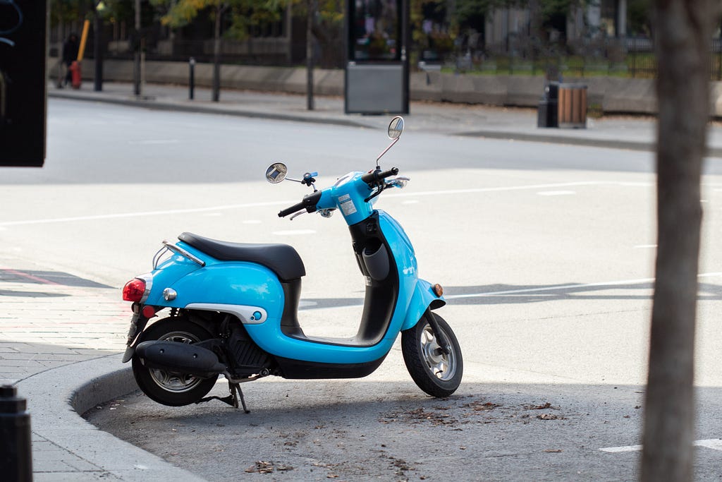 A blue scooter parked along the sidewalk.