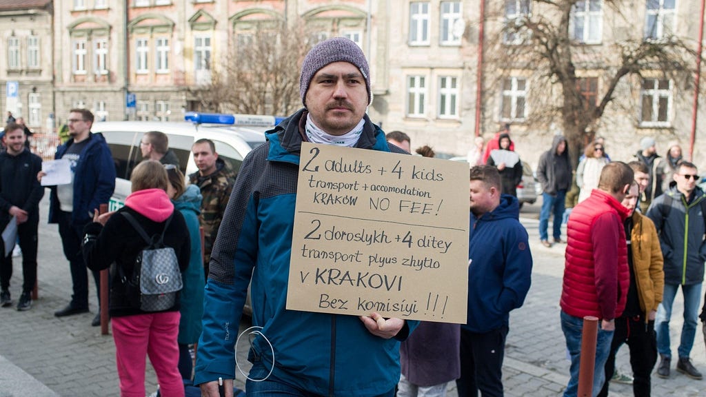 As Ukrainian refugees arrive in Przemsyl, Poland, a man holds a sign offering free housing in Krakow, February 26, 2022. Photo by Nathan Laine/Abaca Press/Alamy