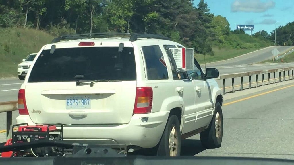 An SUV with a wall-mounted air conditioning unit mounted into the rear passenger-side window.