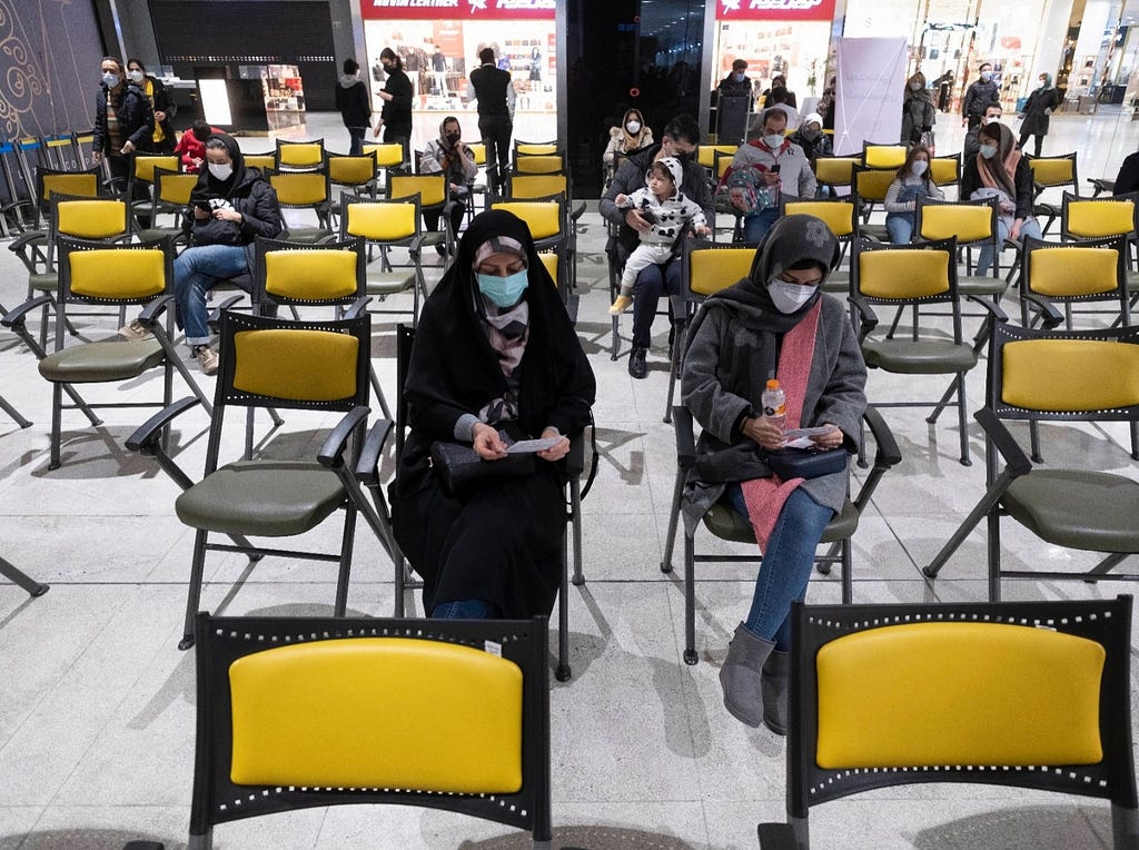 Two women wait to receive a COVID-19 vaccination at the Iran Mall shopping center in western Tehran, Iran, February 5, 2022. Photo by Morteza Nikoubazl/Reuters