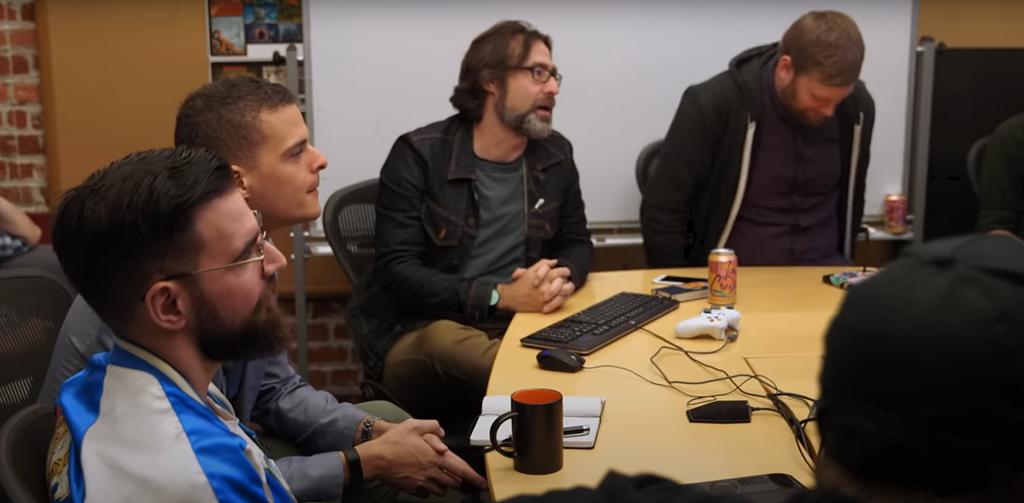 A mixture of Double Fine leads and Starbreeze publisher representatives sit around a table, discussing the state of Psychonauts 2