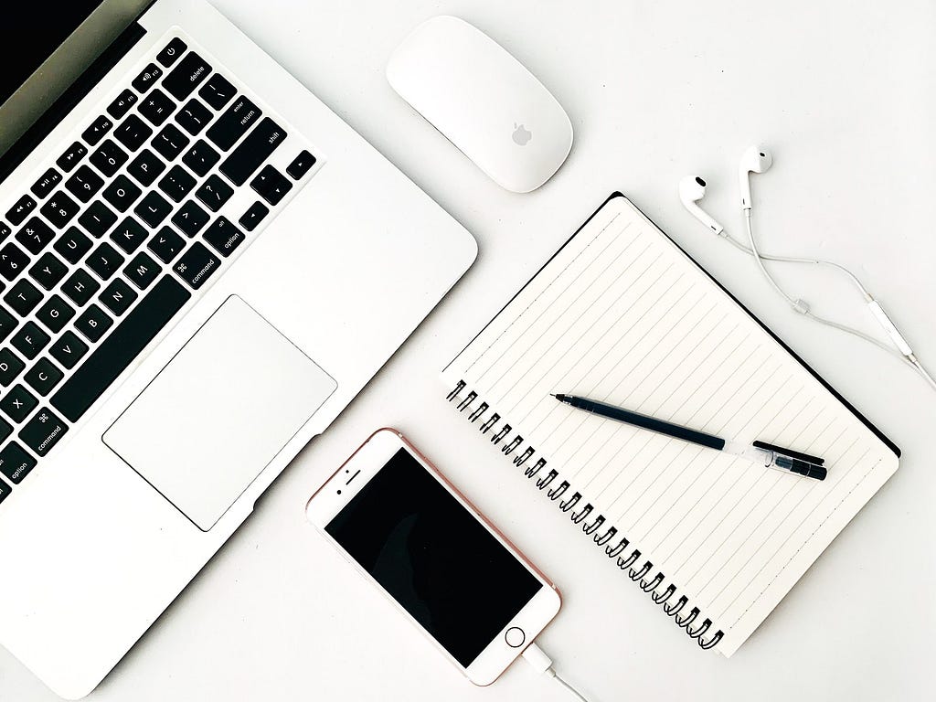 Laptop, notepad and smartphone on a white desk